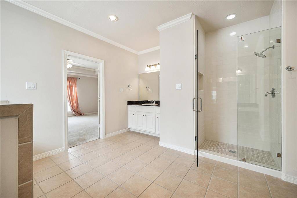 The primary bath also includes a sleek, glass-enclosed standing shower, combining style and functionality for a refreshing experience.