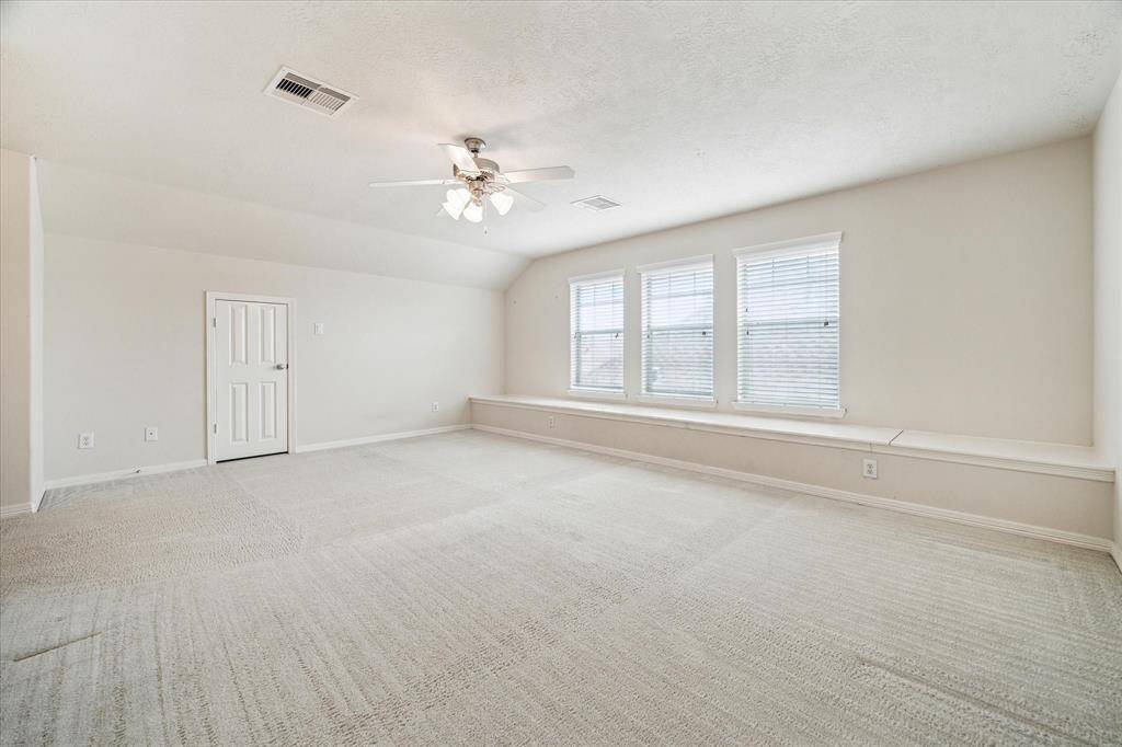 The game room features an extended sitting area with large window panels that flood the space with natural light while offering stunning views of the front yard, creating a bright and inviting atmosphere.