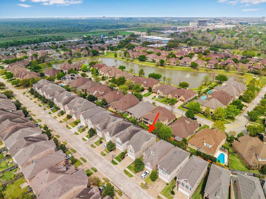 A breathtaking aerial view of the beautiful Terraces on Memorial community, showcasing its picturesque lake and scenic walking trails—perfect for leisurely strolls and enjoying nature.