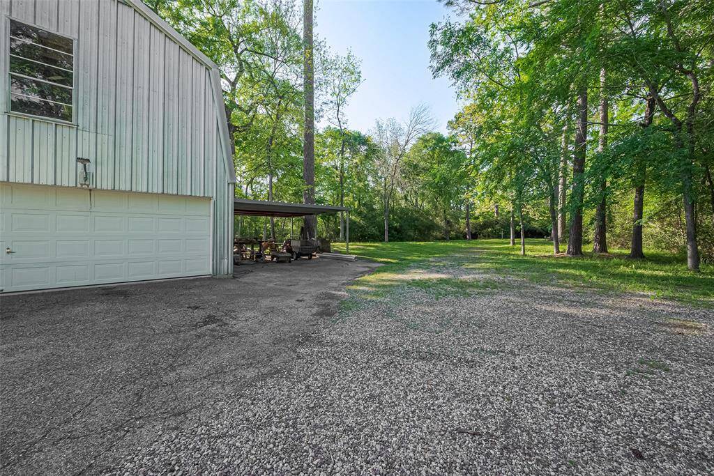 Two-story workshop with an attached two-car carport, offering ample space and convenience. Features high ceiling downstairs, workbench, power, 1/2 bath, and additional storage or workspace upstairs.