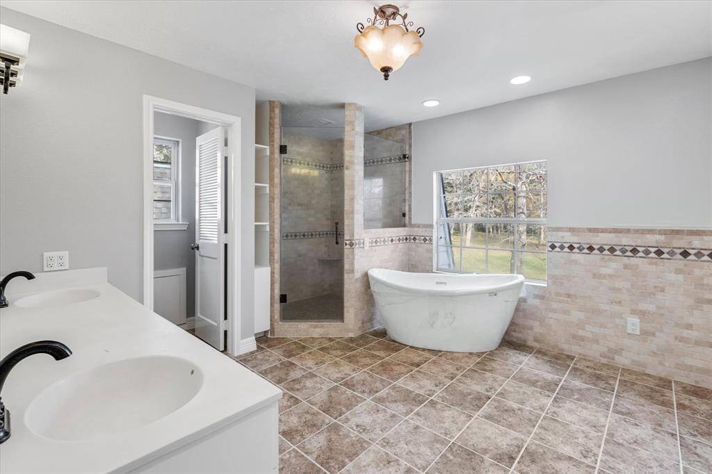 The second floor Primary Bathroom features a walk in shower, a bathtub with a view, a private toilet, and two conjoined handsinks.