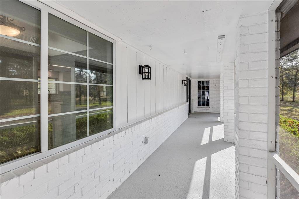 A second view of the enclosed front porch featuring a glance into the home through windows.