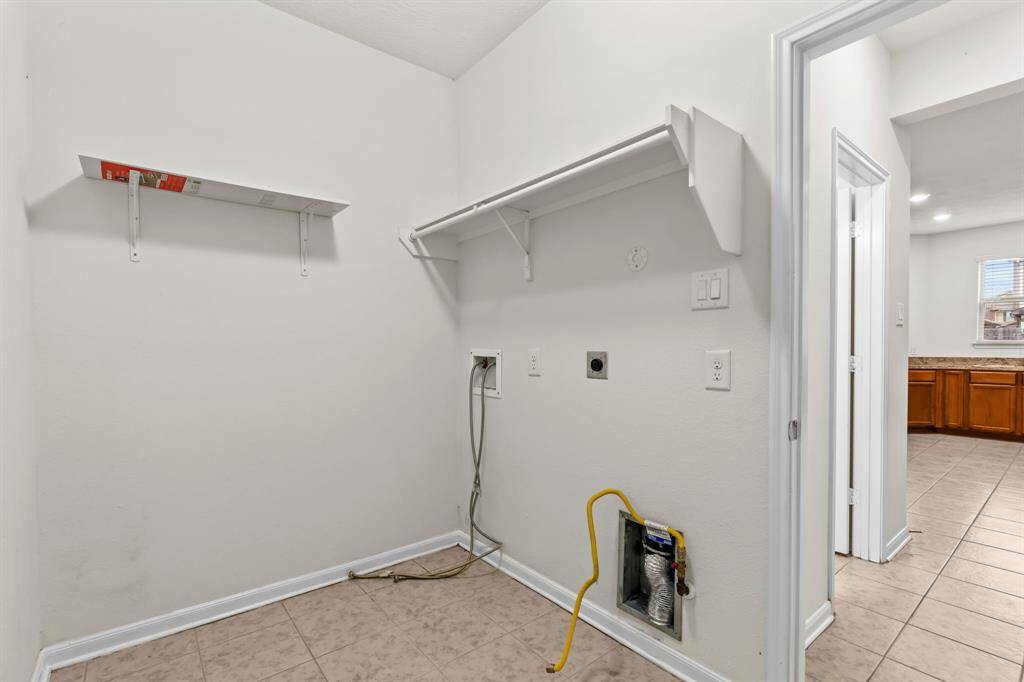 This photo shows a bright, spacious room with clean beige carpeting and neutral-colored walls. It features a large window providing natural light, and an open doorway leading to another room, suggesting a versatile space that could be used as a living area or bedroom.