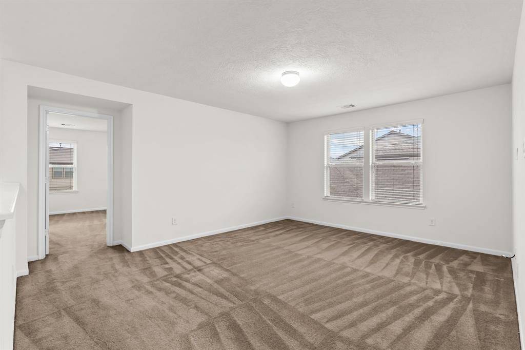 2nd floor spacious, carpeted room with neutral walls with recessed lighting. It features a partially open layout with a half-wall and access to additional rooms, offering a versatile space for various design possibilities.