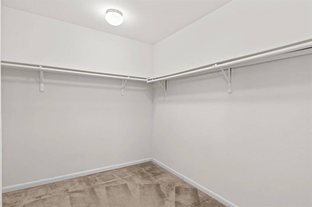 This spacious bedroom features clean, neutral walls and carpeting, with two large windows providing ample natural light. Ideal for creating a cozy personal retreat.