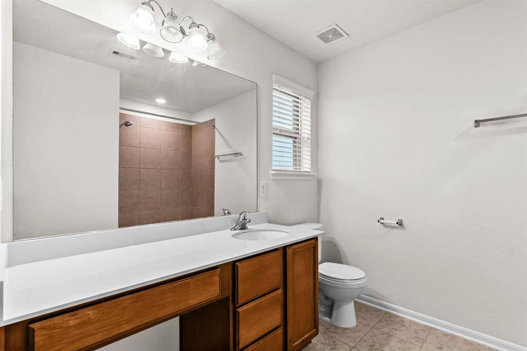 Spacious room with neutral walls and carpet, featuring a central ceiling light. The room is bright with a clean, open layout leading to an adjacent area through a doorway.