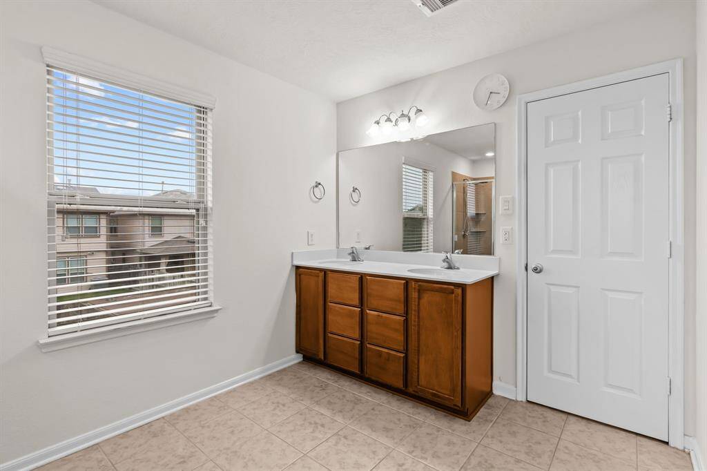This photo shows a spacious, clean, two-car garage with a white automatic door and ample overhead lighting. Ideal for parking and storage.