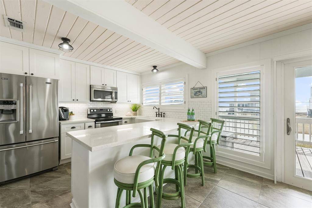 With an open layout and a breakfast bar with stylish seating, this kitchen seamlessly connects to the outdoor deck for effortless indoor-outdoor living.