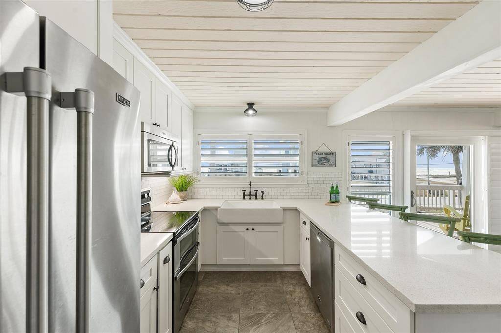 This stunning coastal kitchen features a charming farmhouse sink and a spacious, open layout, making it perfect for entertaining and creating memorable gatherings.