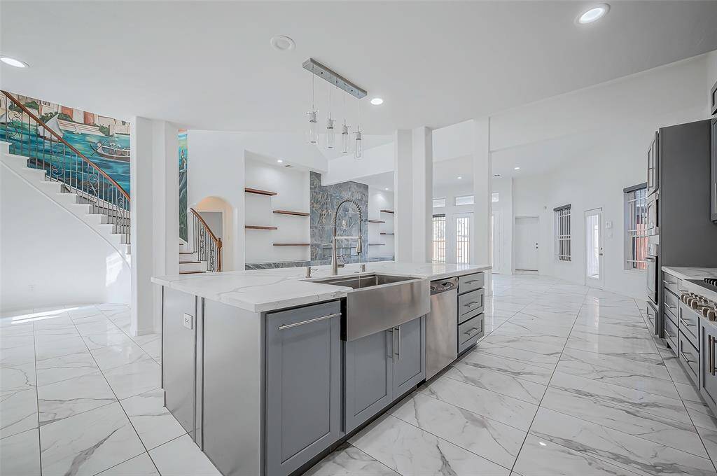 Large center island with a drop-down farm sink and overhanging pendant lights.