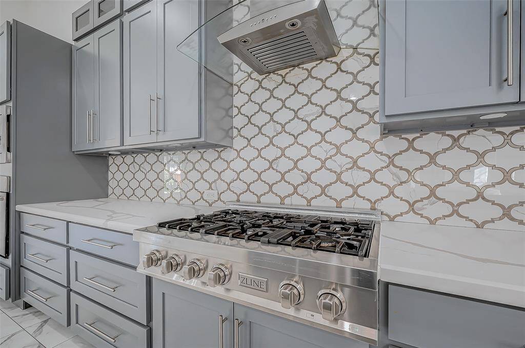 Stainless steel appliances, including a Zline six-burner, gas stove with SS and glass hood. Beautiful tile backsplash!