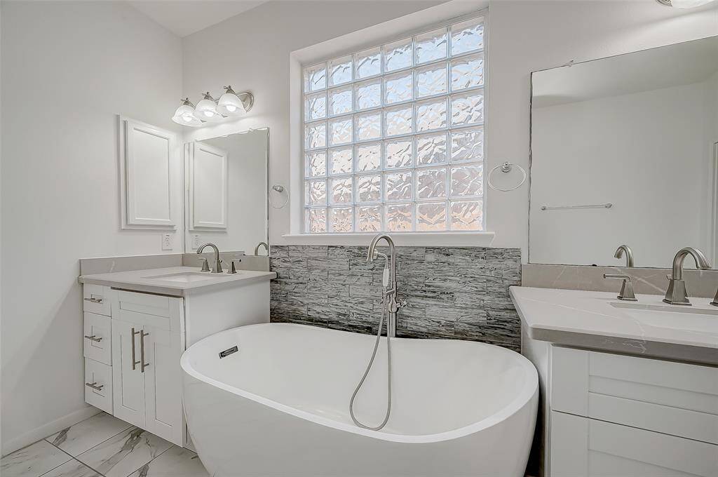 The remodeled primary bathroom includes double vanities, a modern freestanding tub, a walk-in shower, and a large closet with shelving and hanging racks.