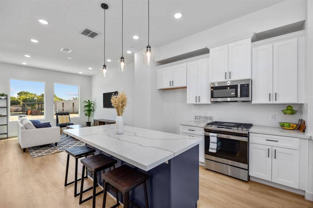 Modern, gourmet kitchen with abundant natural light, quartz countertops, and stainless steel appliances