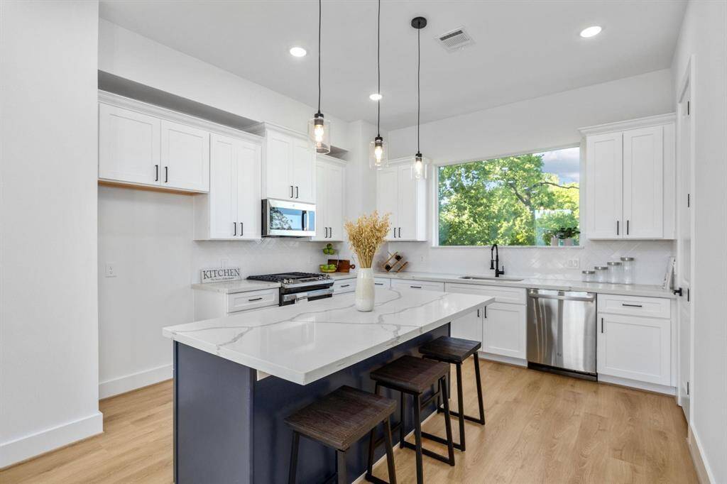 Modern, gourmet kitchen with abundant natural light, quartz countertops, and stainless steel appliances
