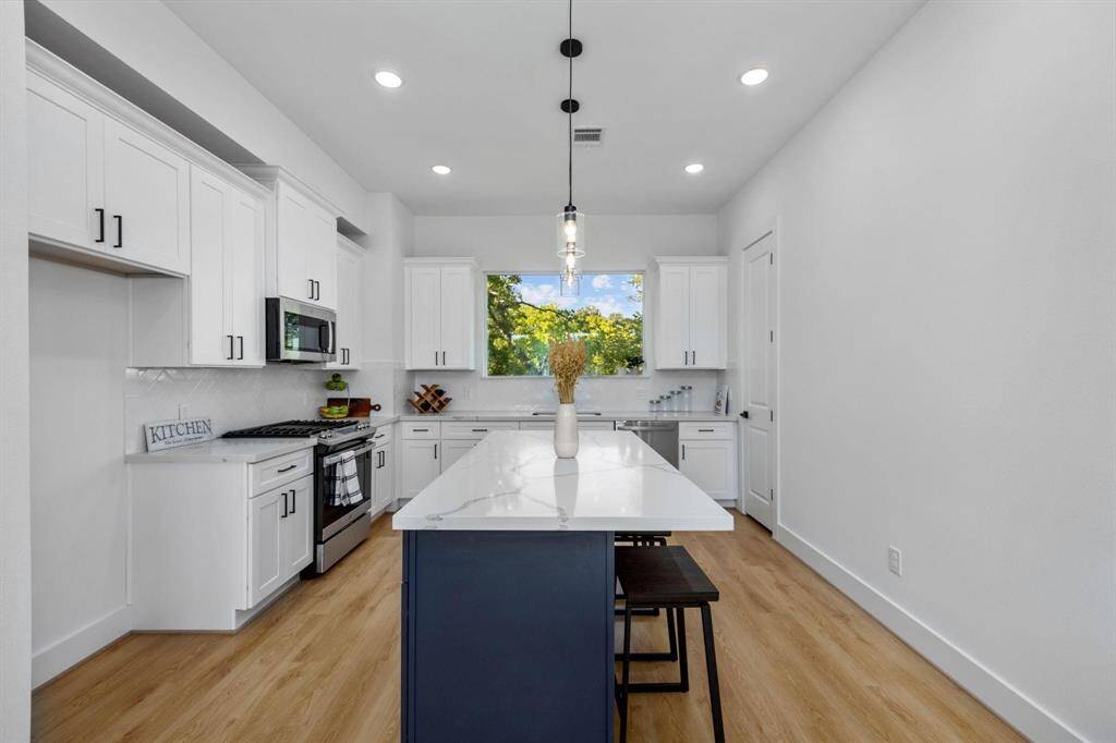 Modern, gourmet kitchen with abundant natural light, quartz countertops, and stainless steel appliances