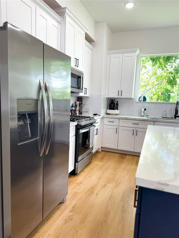 Modern, gourmet kitchen with abundant natural light, quartz countertops, and stainless steel appliances
