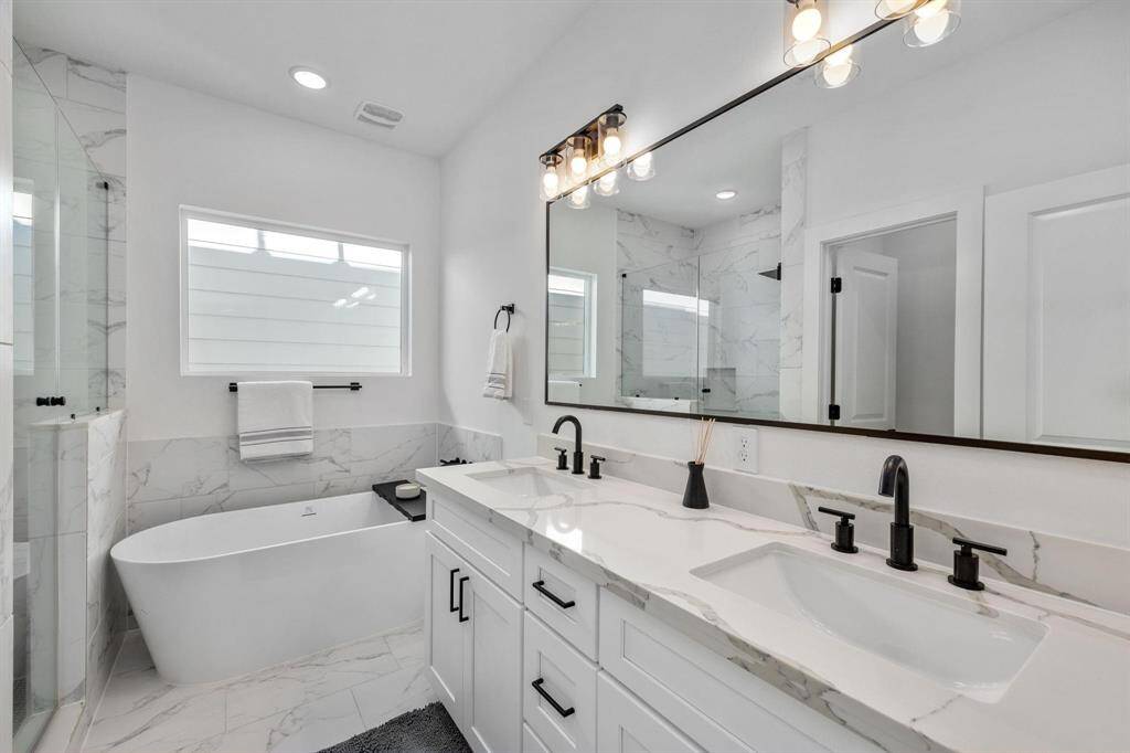 Primary bathroom oasis with double vanity, separate soaking tub, and shower