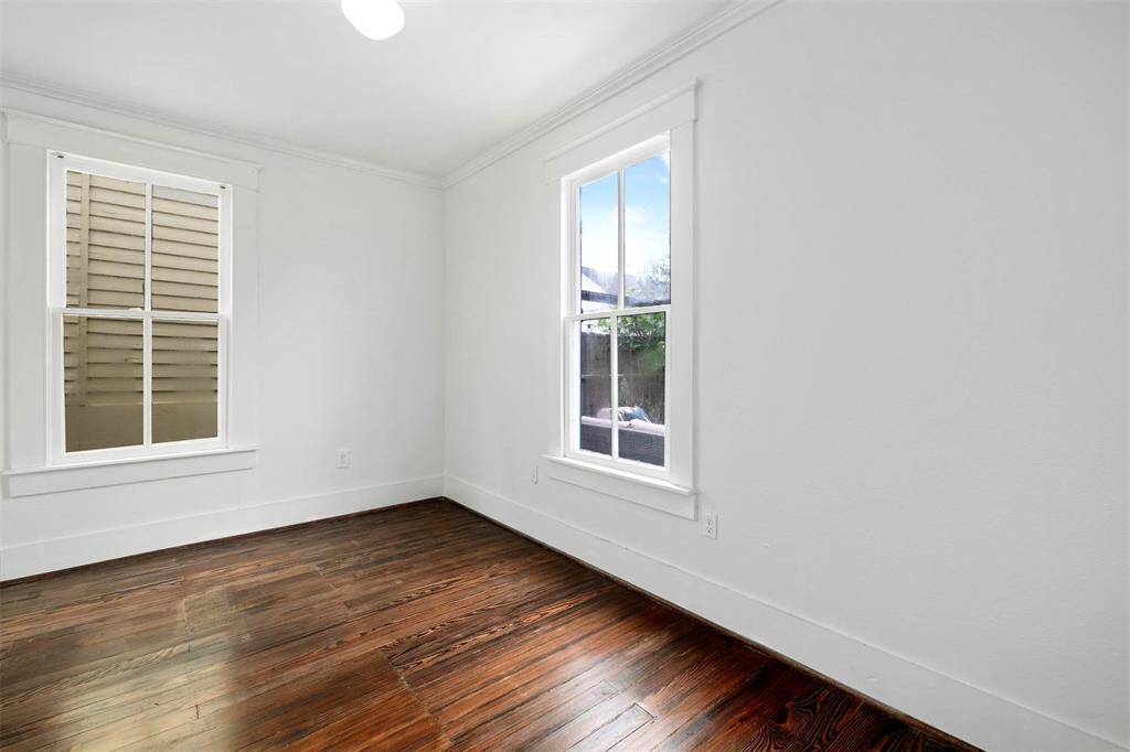 Bright room with white walls, large windows, and rich hardwood floors, offering ample natural light. Ideal for a bedroom, craftroom or office space.