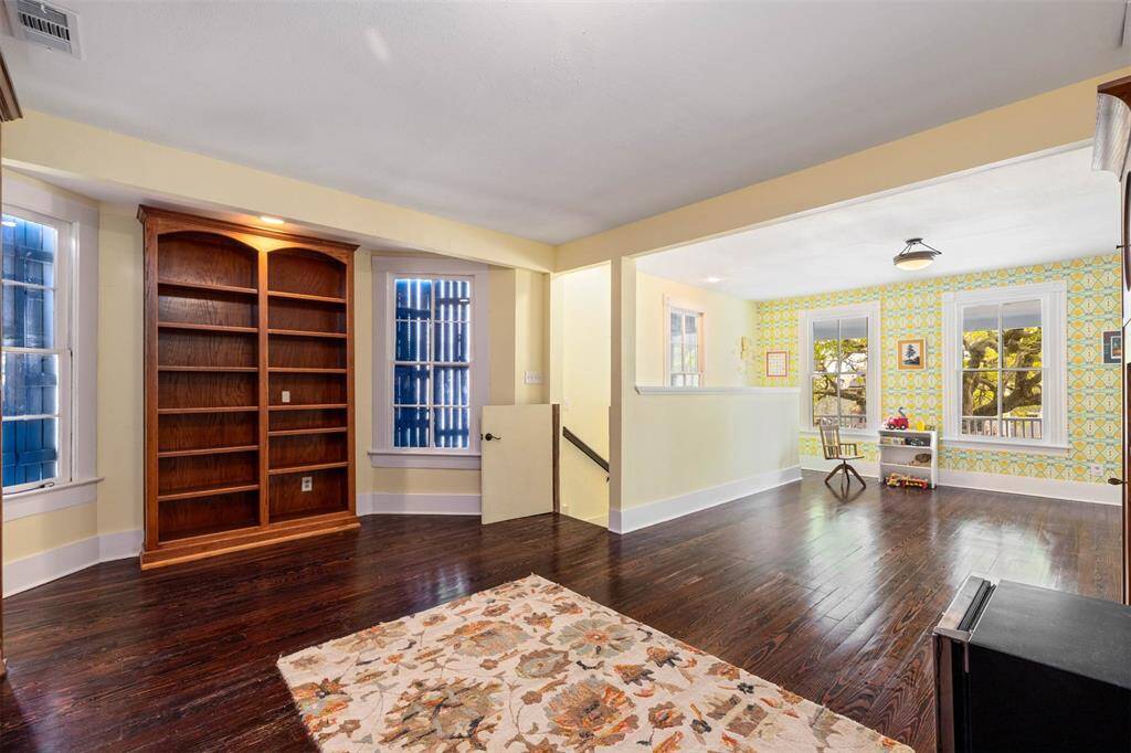 The gameroom space is open and versatile, with a charming nook perfect for a reading or play area, accented by vibrant wallpaper.