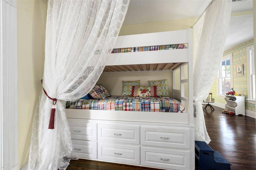 This cozy and charming bunk bed has sheer curtains for privacy and built-in drawers for storage.