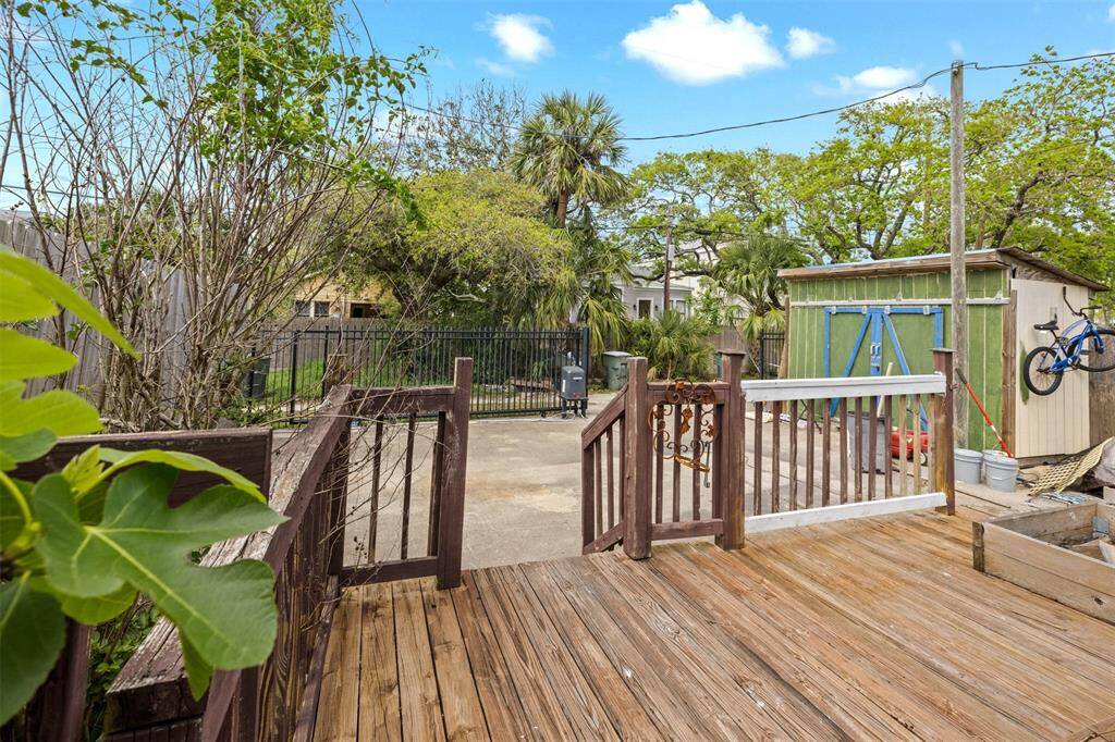 Charming backyard with a wooden deck, small storage shed, and a fenced area. Lush greenery and mature trees provide a serene setting, perfect for relaxation and outdoor activities.
