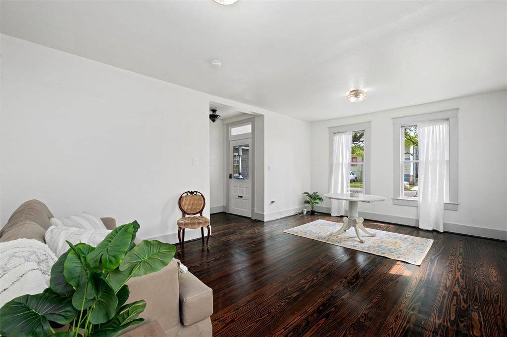 Another view of the bright living room with dark hardwood floors, white walls, and plenty of natural light from large windows.