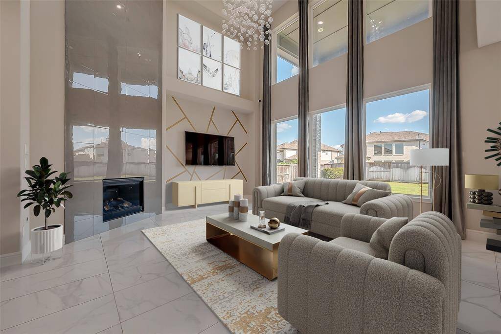 Grand Family Room: The heart of the home, this space impresses with a wall of windows, letting natural light pour in. Dramatic floor-to-ceiling window drapery, a showstopping tile fireplace, and an overhanging chandelier add charm and character, making it the perfect space for gatherings or relaxing.( virtually staged)