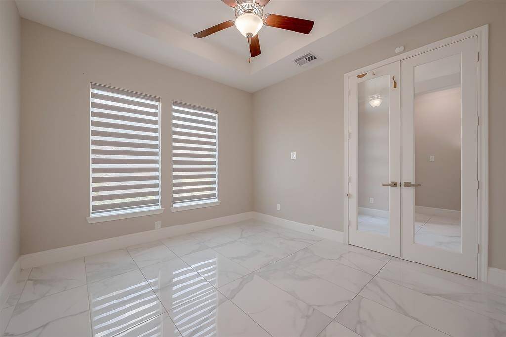 Home Office: Tucked to the side of the entry, the office is an ideal workspace featuring double glass doors, a tray ceiling, and tranquil views of the front yard. Custom roller shades for privacy and style throughout the home.