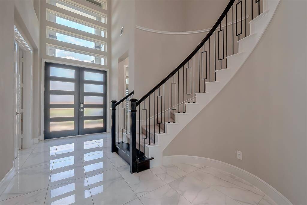 As you step inside the grand 2-story entryway, you're welcomed by the warmth of marbled tile flooring throughout the first level. Upgraded modern windows above the entry doors allow natural light to fill the space, creating an inviting ambiance.