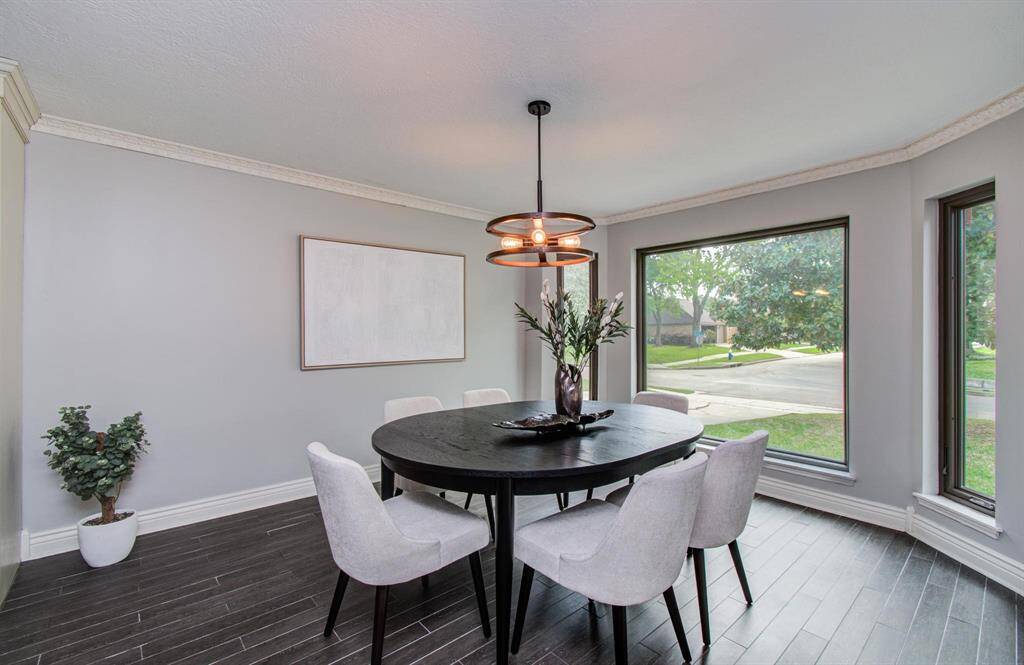 The dining room adjoins the kitchen, boasting large picture windows offering a view of the outdoors and allowing natural light to flood the space.