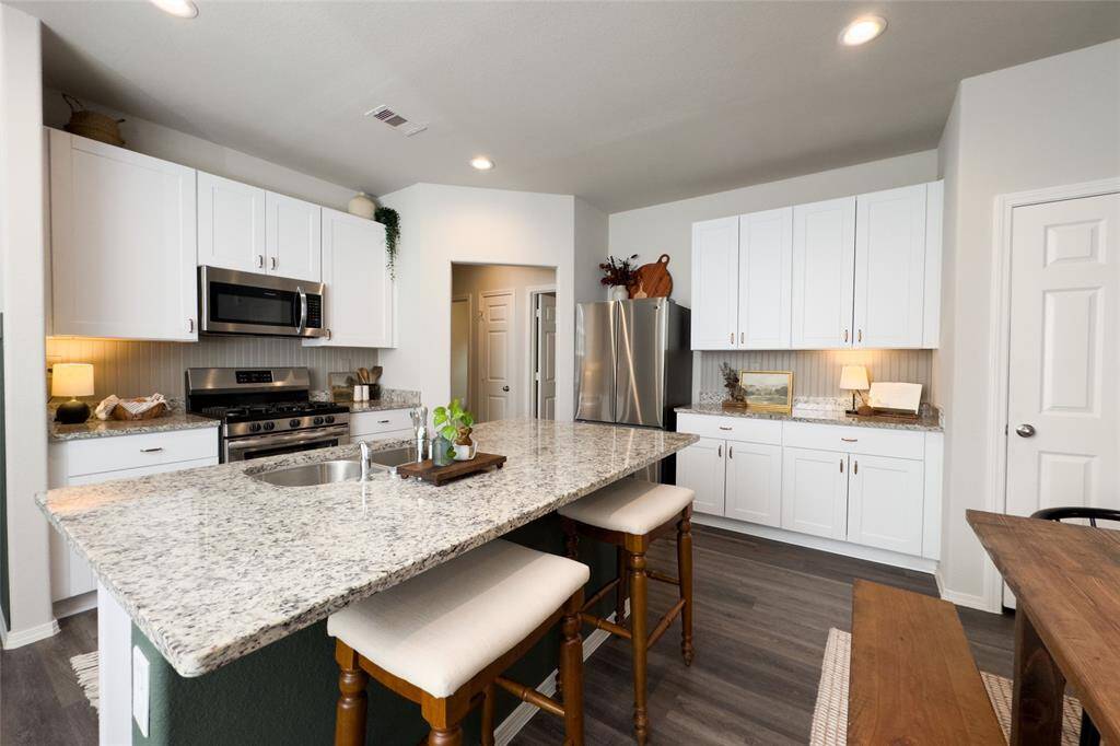 Check out this gorgeous kitchen featuring 42' white kitchen cabinets, updated gold hardware, updated backsplash, granite countertops, and freshly painted island that pulls everything together perfectly.