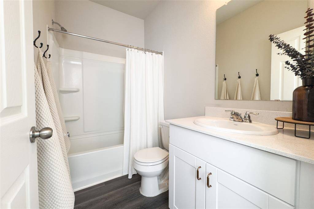 Hallway bathroom with updated gold hardware, and granite countertop.