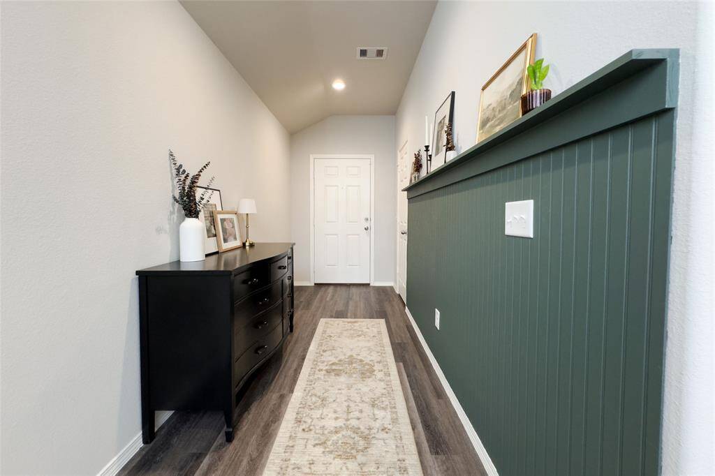 Upon entry, you're greeted by beautiful rustic waterproof vinyl flooring that flows seamlessly throughout the main areas of the home. To the left, a striking forest green accent wall adds a stylish and inviting touch.