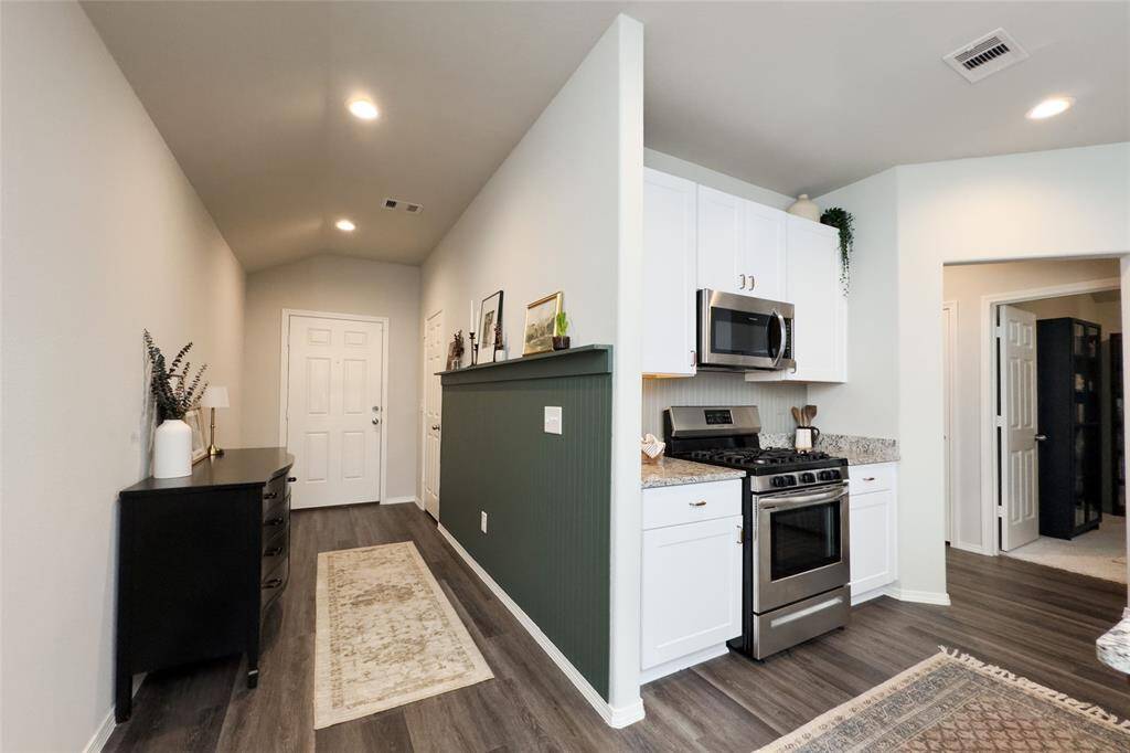 Upon entry, you're greeted by beautiful rustic waterproof vinyl flooring that flows seamlessly throughout the main areas of the home. To the left, a striking forest green accent wall adds a stylish and inviting touch.
