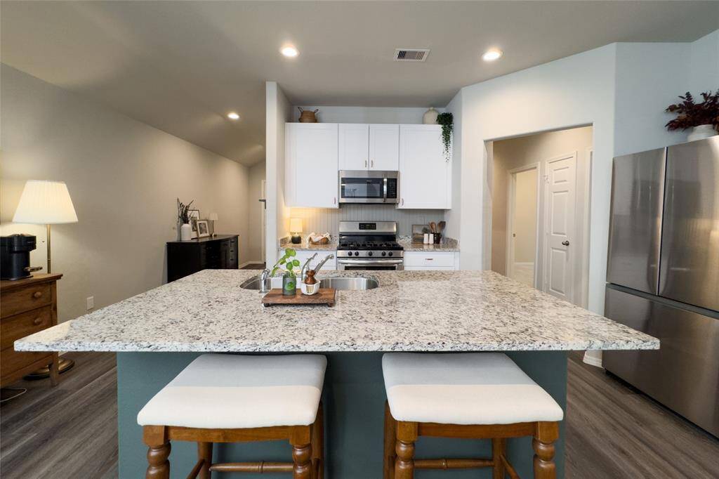 Check out this gorgeous kitchen featuring 42' white kitchen cabinets, updated gold hardware, updated backsplash, granite countertops, and freshly painted island that pulls everything together perfectly.