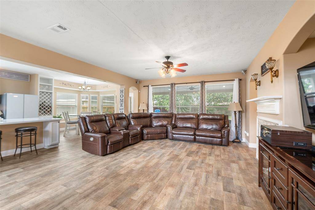 Spacious living room with wood-look tile flooring, a cozy gas fireplace, and abundant natural light. Perfect for relaxing or entertaining.