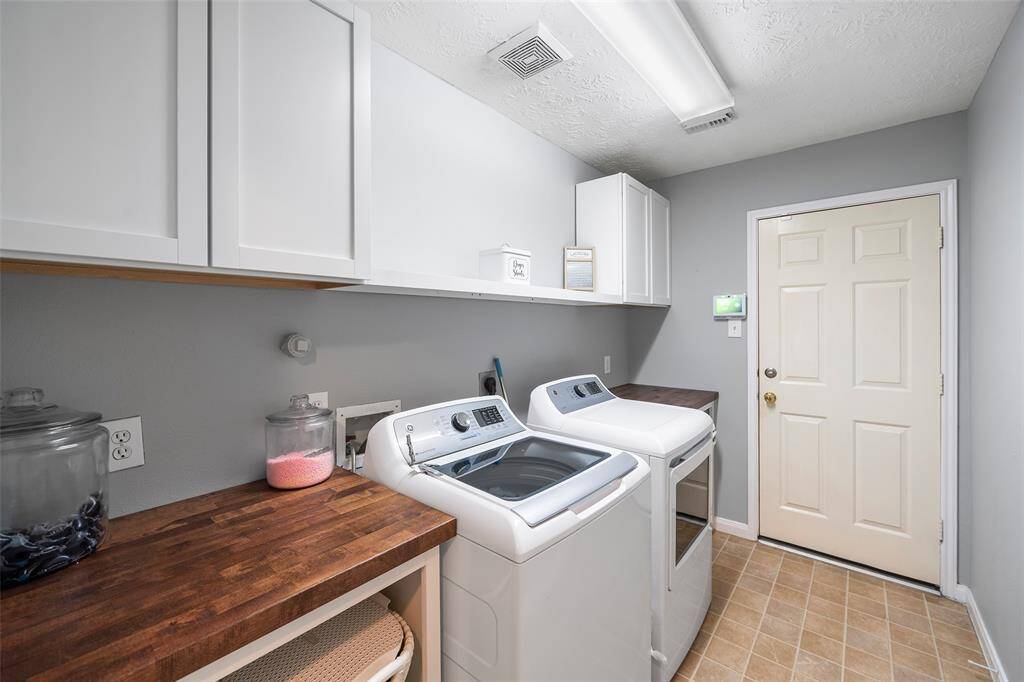 A spacious utility room with ample shelving for organization. It features connections for both gas and electric dryers, making it versatile and functional for all laundry needs.