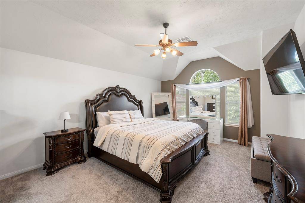 Unwind in this beautifully appointed primary suite with soft carpeting, warm color palette, high ceilings, and generous windows that invite natural light while offering privacy.