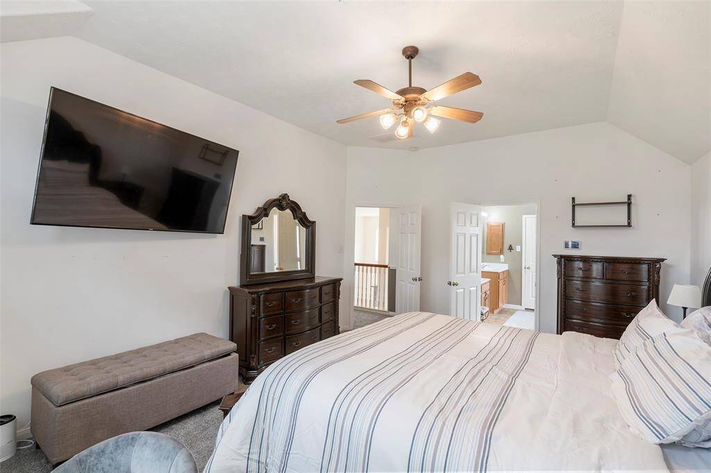 Secondary bath features tile flooring, bath/shower combo with tile surround, stained wood cabinets, beautiful light countertop.