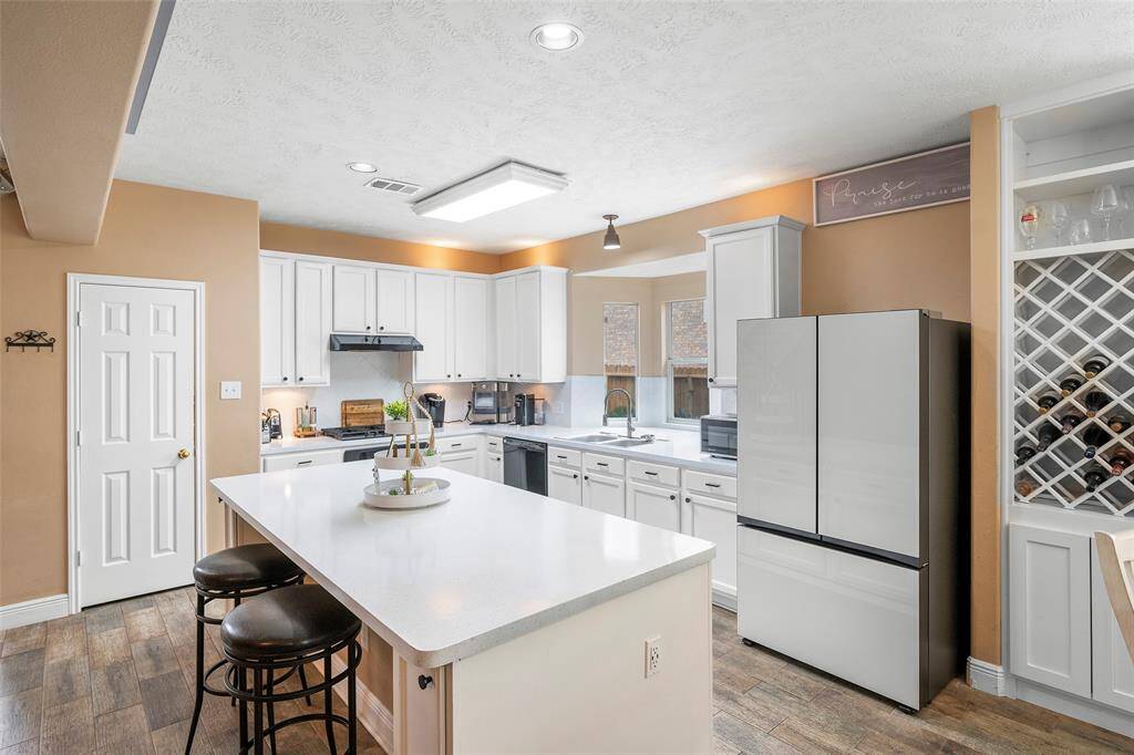 Bright, updated kitchen with white cabinetry, large island, and modern appliances. Open, functional layout perfect for everyday living and entertaining.