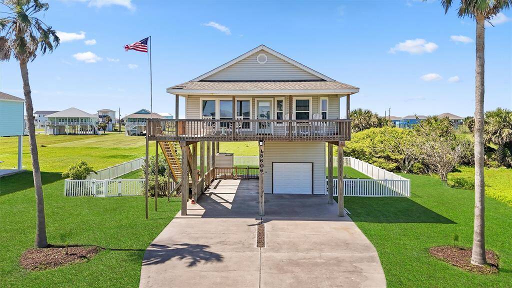Front view of the home showcasing its elevated design, spacious balcony, and fenced yard.