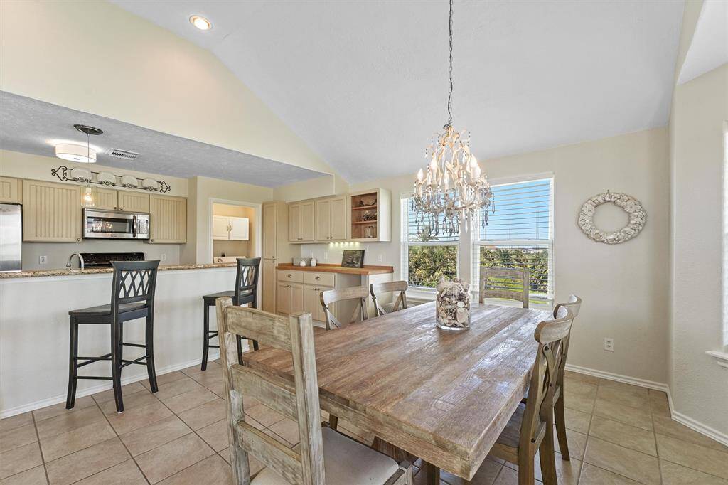 Open-concept dining and kitchen area with vaulted ceilings and charming coastal finishes.