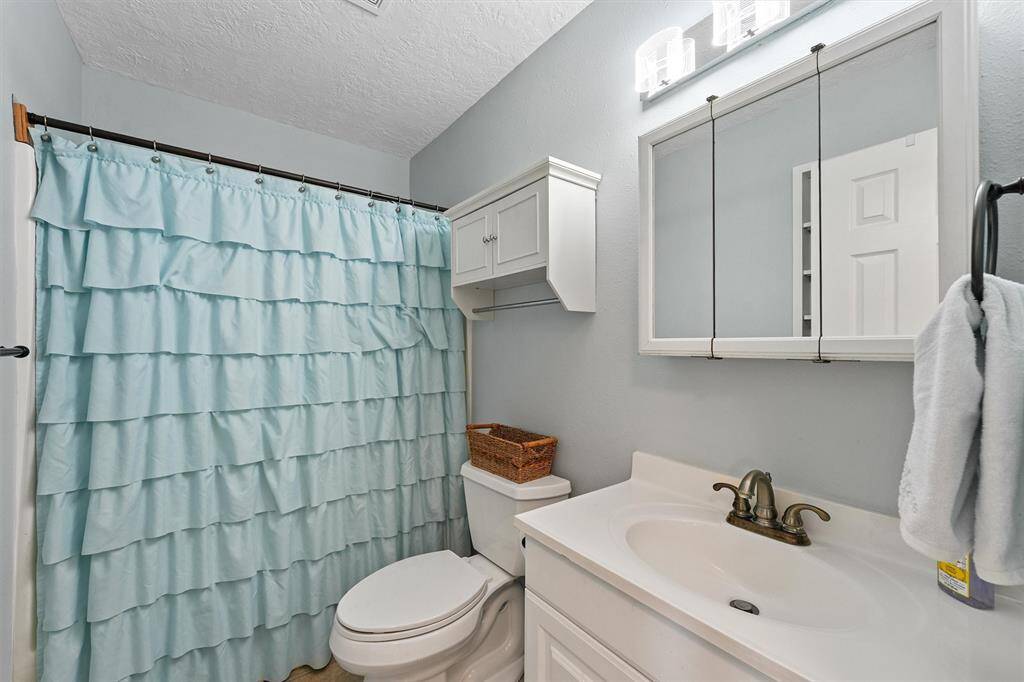 Full bathroom with updated lighting, vanity, and a soft coastal color palette.