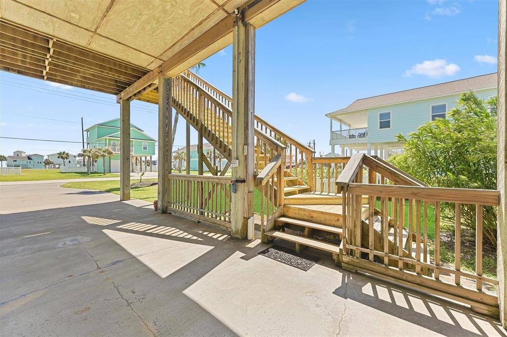 Side view of the staircase entry with gated access and lush greenery for privacy.