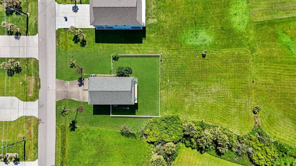 A bird’s-eye perspective highlights the large fenced yard and the peaceful, uncrowded surroundings of the property.