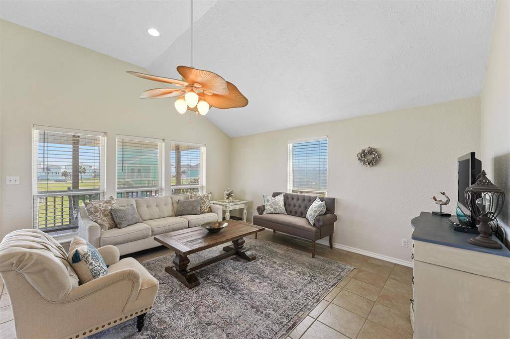 Light and bright living room with vaulted ceilings and walls of windows showcasing peek-a-boo ocean views.