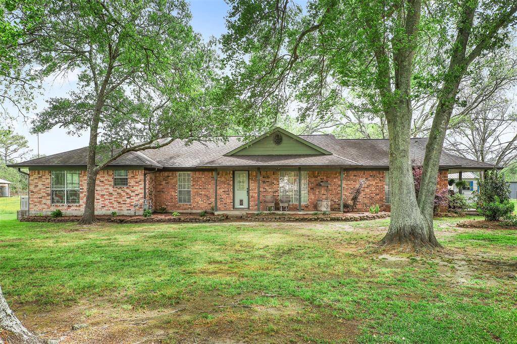 This charming brick ranch-style home has a spacious front yard and mature trees. It features large windows and a welcoming front entrance, offering a cozy and inviting atmosphere.