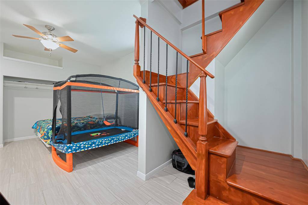 A wooden staircase with iron balusters, leading to a lower level where you will find a bonus room, perfect for a child's room or guest space.
