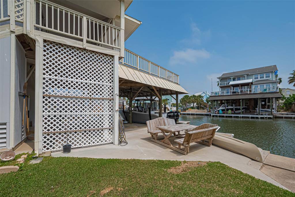 Spacious deck with a boat slip, offering direct canal access. The outdoor seating area is perfect for relaxation, surrounded by a well-maintained lawn and scenic views of neighboring homes.