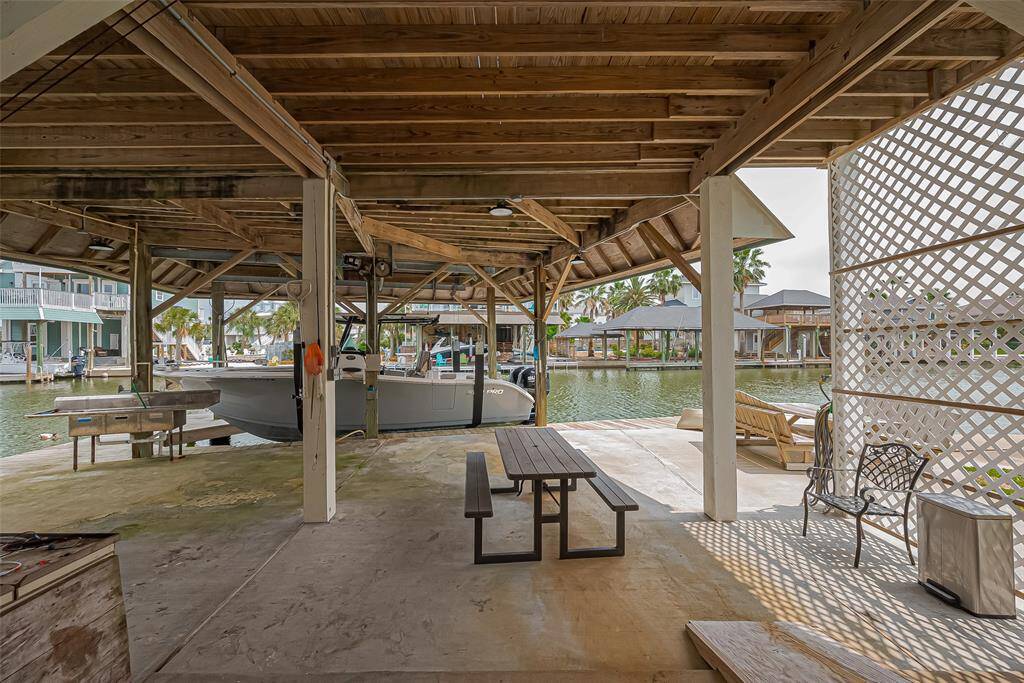 Covered boat dock with seating areas, providing direct waterfront access. The space features a wooden structure, ample shade, and a peaceful view of the surrounding water, ideal for relaxation and outdoor activities.